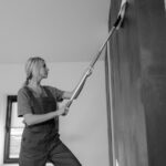 Grayscale Photo of a Cleaner Wiping a Tiled Wall